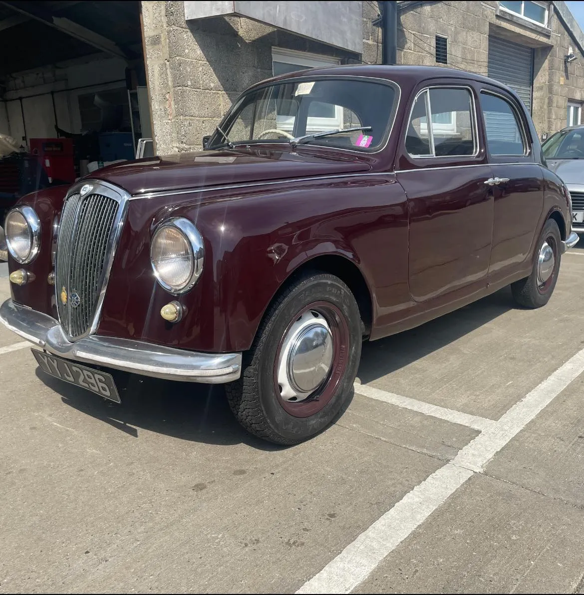 A maroon car is parked in a parking lot.