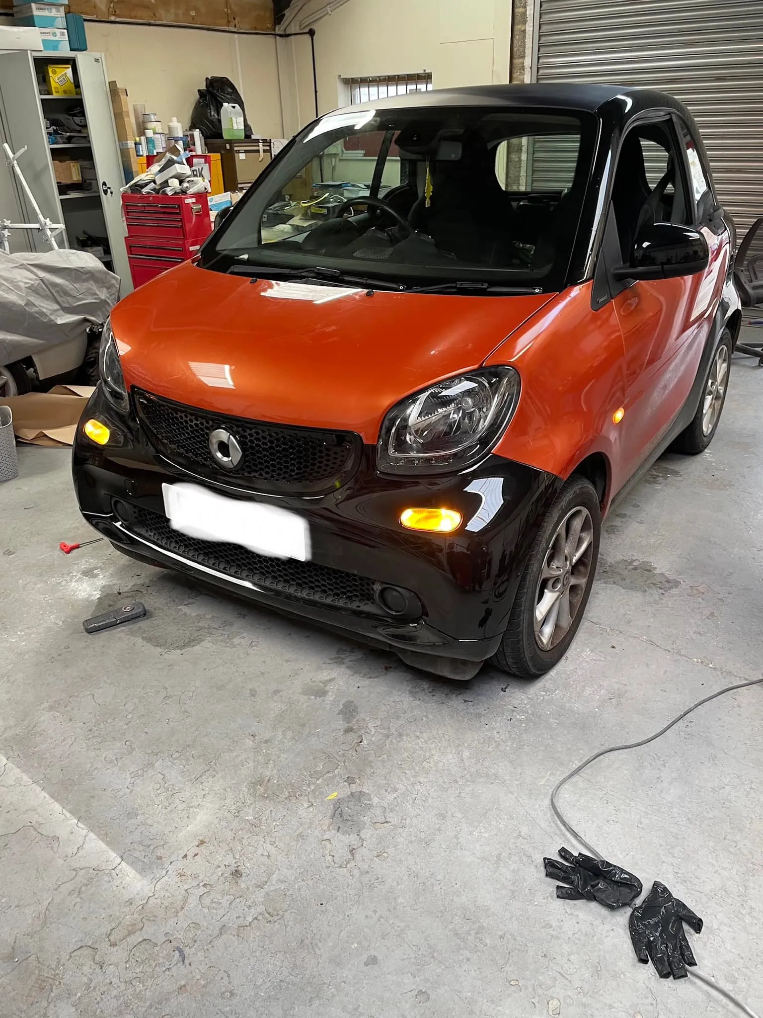 A small orange car parked in a garage.